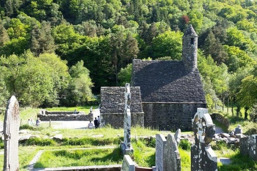 A stone building with a chimney, surrounded by lush greenery and ancient stone structures. 3