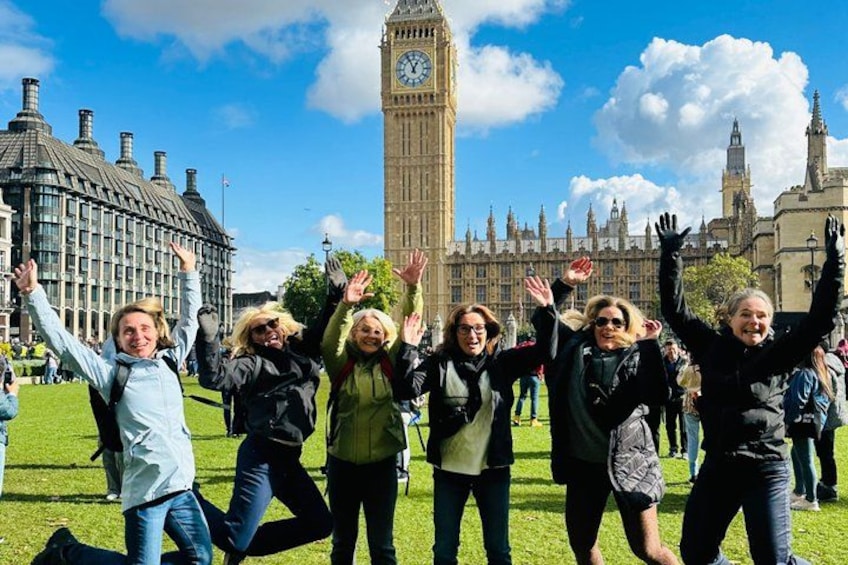 A group of people in a grassy area with the Big Ben clock tower in the background. 2