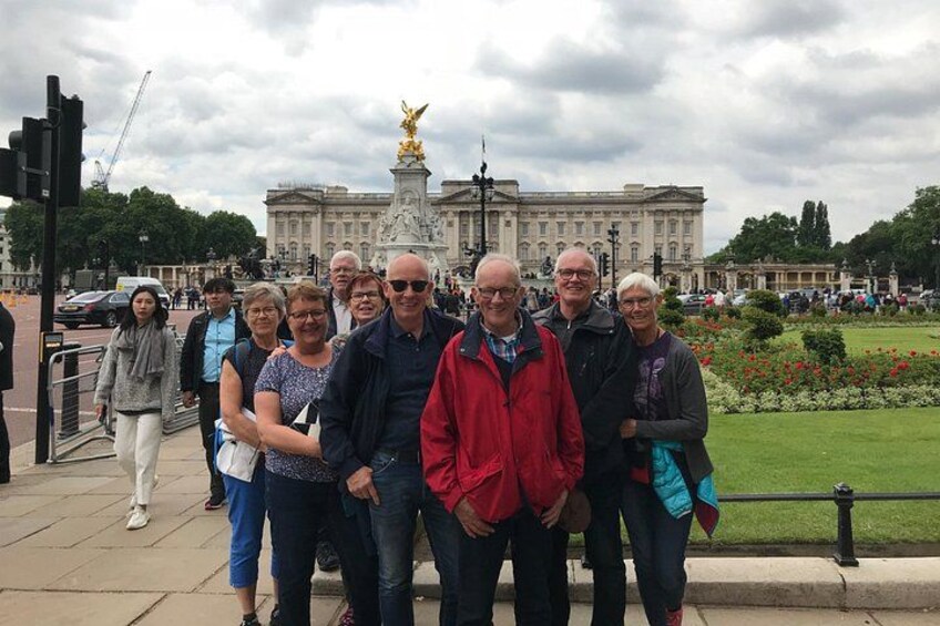 A group of people posing in front of Buckingham Palace with the London Eye in the background. 5