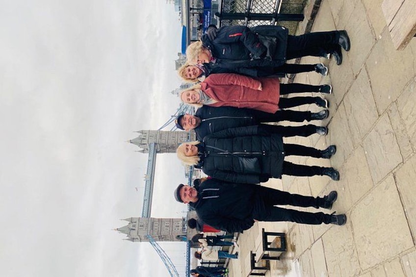 A group of people standing on a paved area with a large bridge and tower in the background. 3