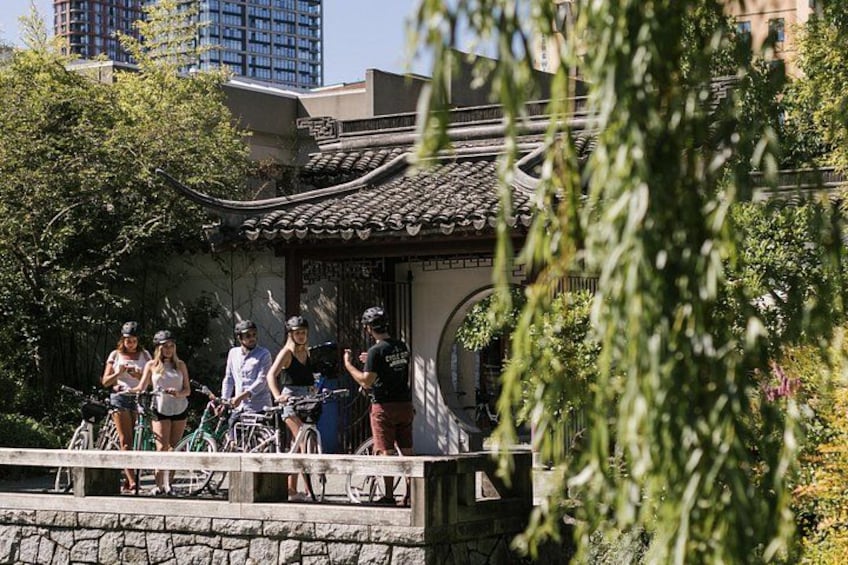 A group of people with bicycles near a traditional building with a tiled roof. 1