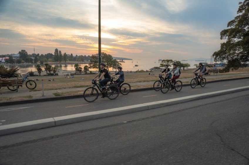 Cyclists riding on a road with a sunset in the background. 4