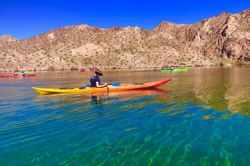 Un kayakista en un kayak amarillo en un lago tranquilo con montañas al fondo. 2