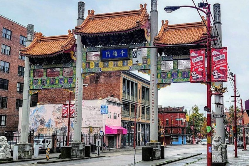 Una puerta tradicional china con decoraciones coloridas, un edificio moderno con un letrero azul y una calle con una pancarta roja. 4