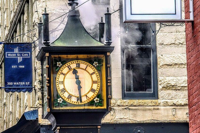 Un reloj antiguo con números romanos, un letrero que indica Cafetería Water St. y la fachada de un edificio de ladrillo. 2