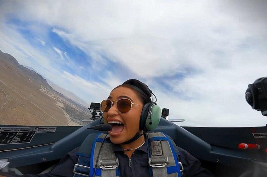 En person i ett cockpit med ett bergigt landskap i bakgrunden. 1