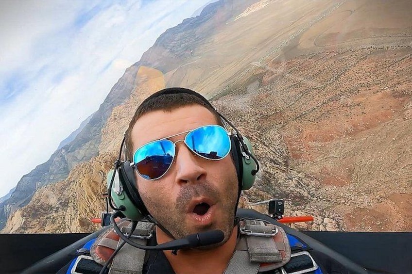 A person in a cockpit with a mountainous landscape in the background. 4