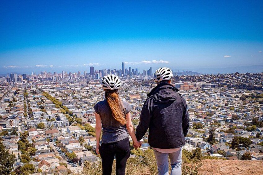 Two people wearing helmets, overlooking a cityscape with a clear sky. 5