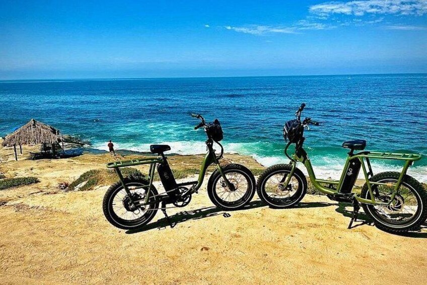 Three bicycles parked on a sandy beach with the ocean in the background. 1