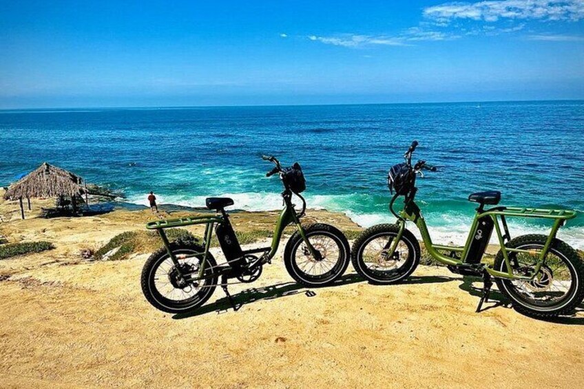 Three bicycles parked on a sandy beach with the ocean in the background. 1