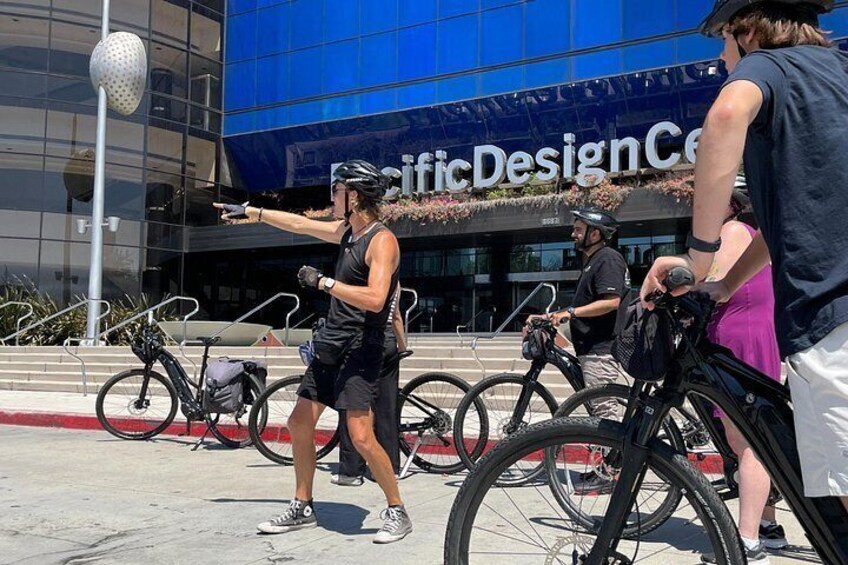 Una persona andando en bicicleta, un edificio con el rótulo 'Design Center' y bicicletas estacionadas cerca. 5