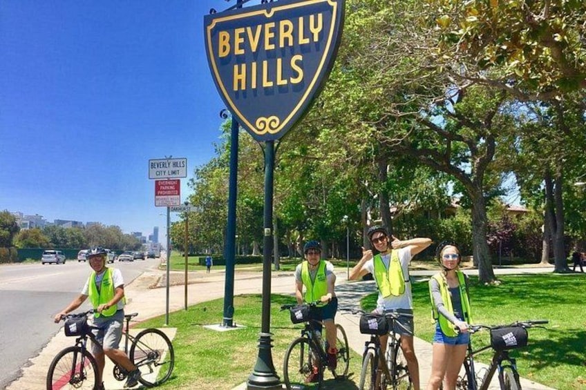 Un gruppo di ciclisti vicino a un cartello con la scritta 'BEVERLY HILLS CITY LIMIT'. 1