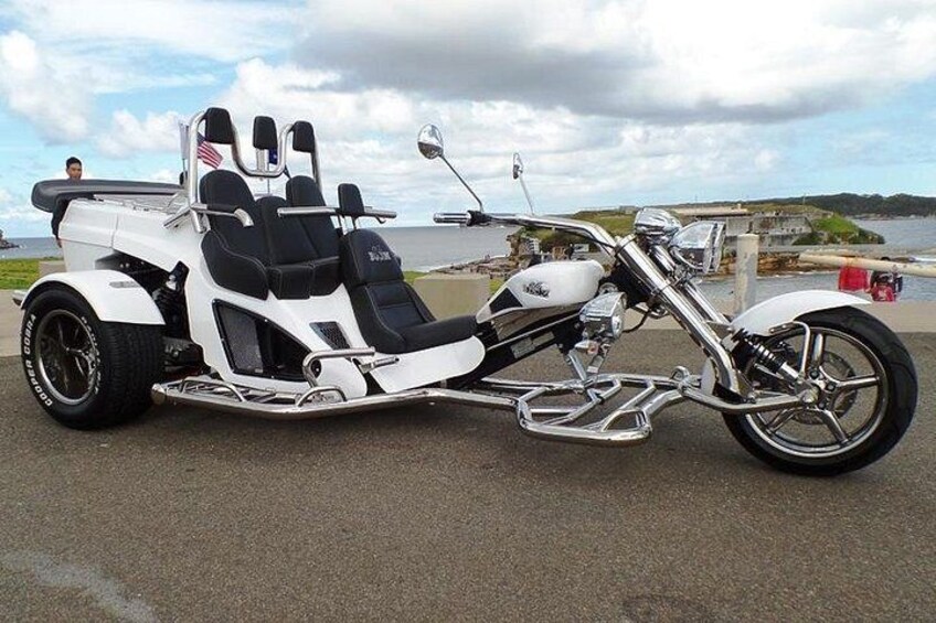 Ein Motorrad mit Beiwagen, abgestellt auf einer befestigten Fläche in der Nähe von Wasser. 4