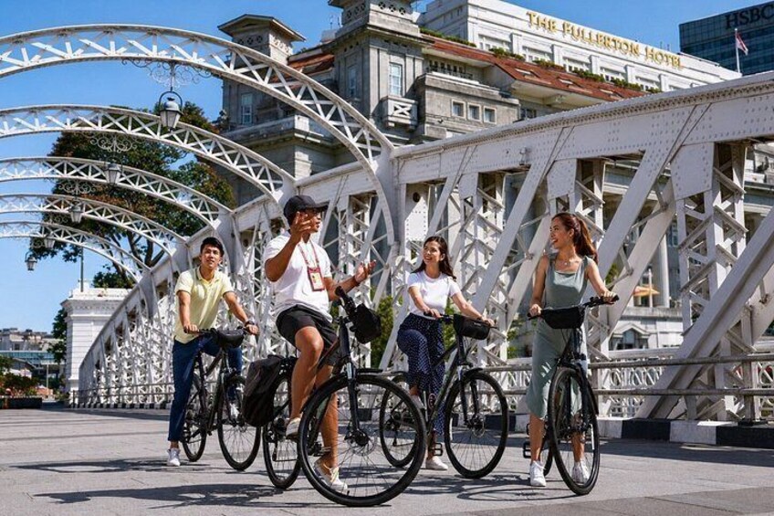 Four people riding bicycles on a bridge with a metal arch structure. 3