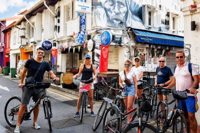 A group of people on bicycles in an urban street with buildings and a large mural. 2