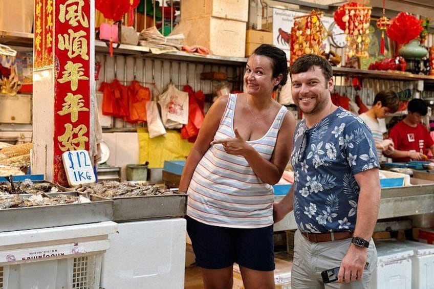 A market stall with seafood, a red sign with Chinese characters, and a person pointing. 2