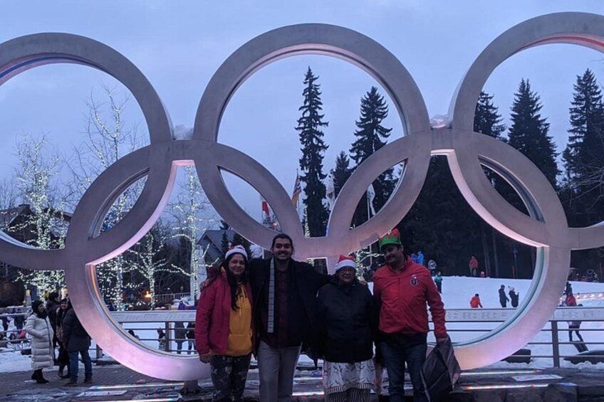 A large Olympic rings sculpture with people standing in front of it. 5