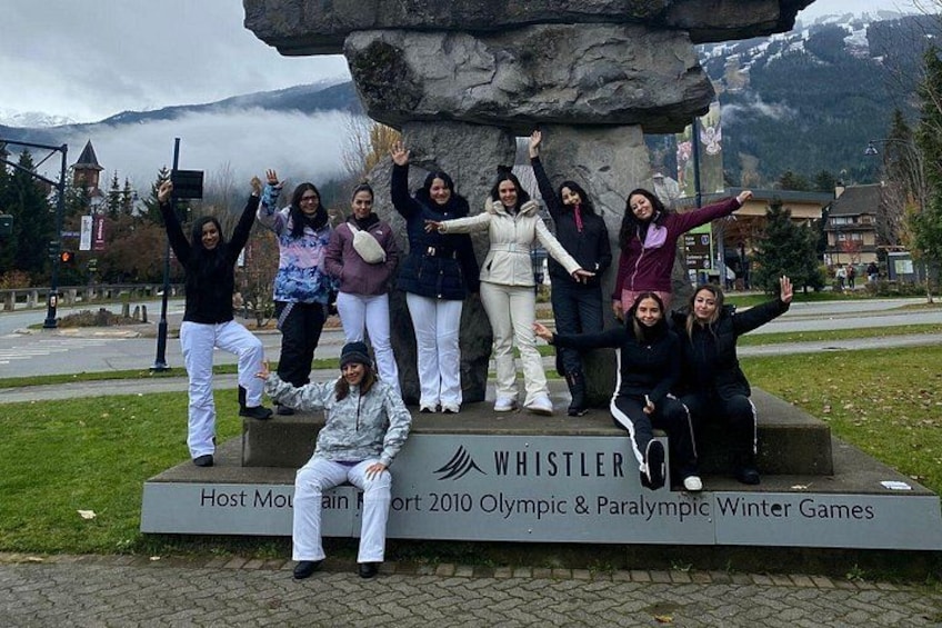 A group of people posing in front of a monument with inscriptions. 1