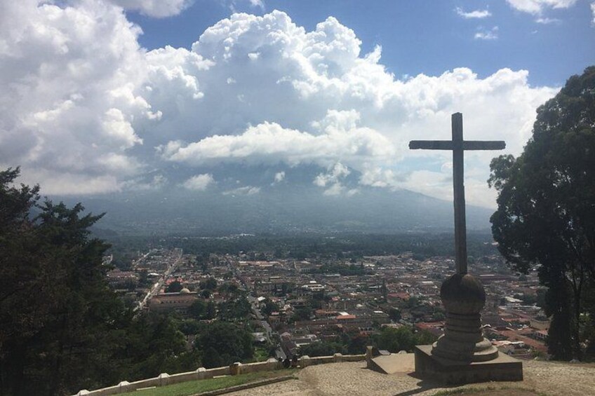 A cross on a hill overlooking a cityscape. 1