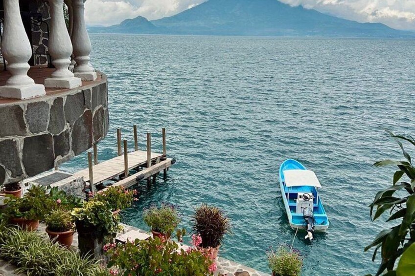 A blue boat on calm water, a stone balustrade, and a mountainous landscape in the background. 3