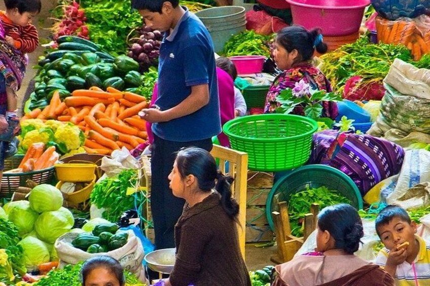 A vegetable market with people shopping and standing around. 2