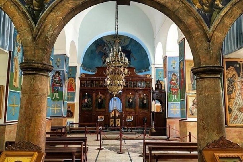 An interior of a church with a wooden altar, a chandelier, and religious icons on the walls. 5