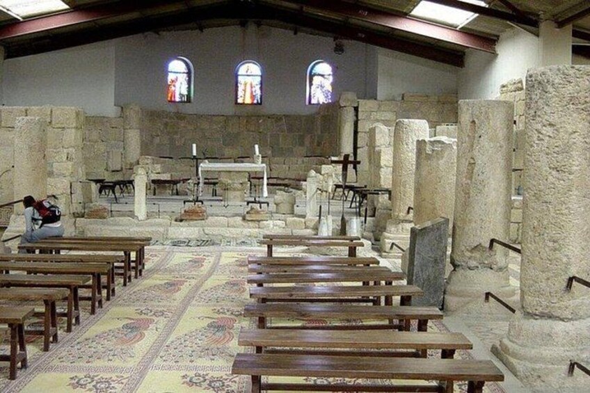 Interior de una iglesia con bancales de madera, columnas de piedra y vidrieras. 4