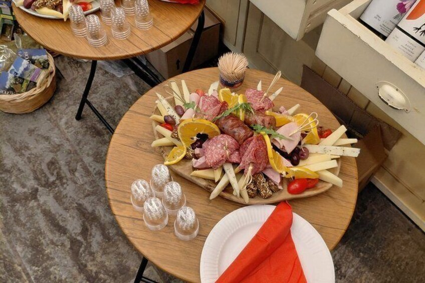 Eine Platte mit verschiedenen Wurstwaren, Käsesorten und Früchten auf einem Holztisch. 5