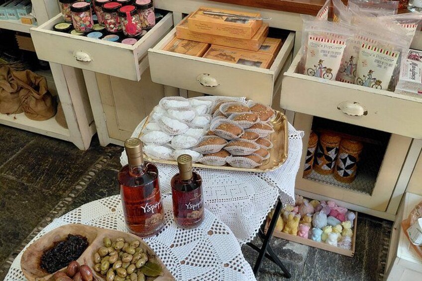 A table with jars of preserves, a basket of cookies, and bottles of syrup. 5