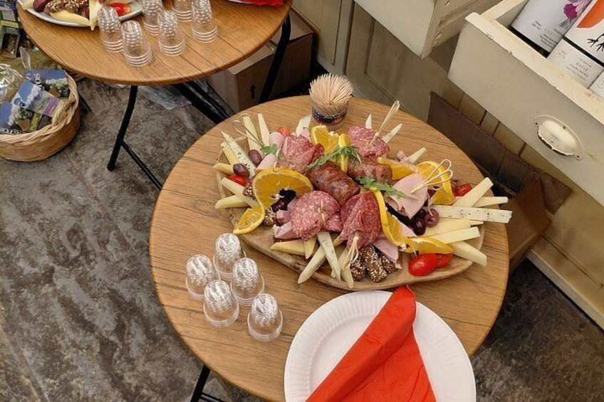 A round wooden table with a charcuterie board, glasses, and a napkin. 4