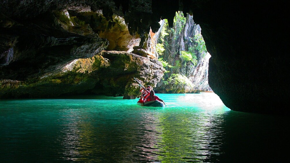 A kayak navigating through a clear turquoise waterway surrounded by rocky cliffs and lush greenery. 1