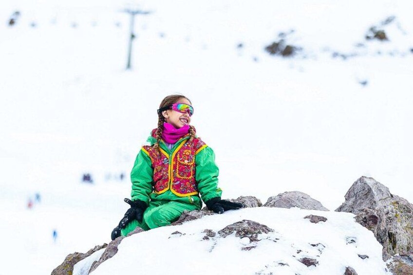 Eine Person sitzt auf einem Felsen in einer verschneiten Landschaft. 2
