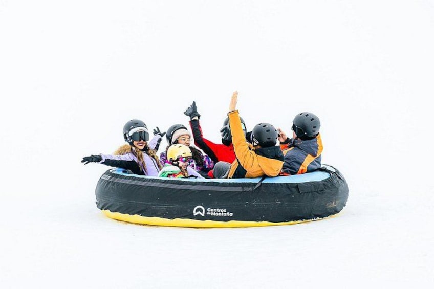 A group of people in a black inflatable raft on a snowy surface. 4