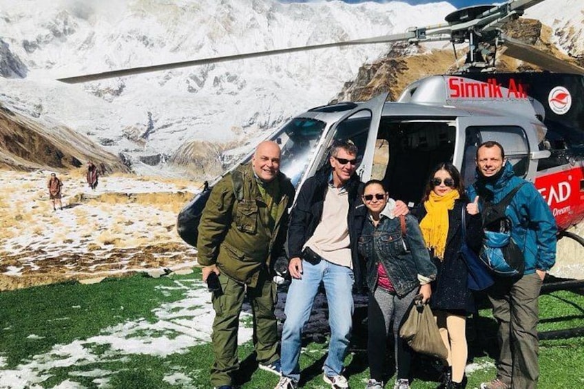 Un grupo de personas frente a un helicóptero, con un paisaje montañoso al fondo. 2