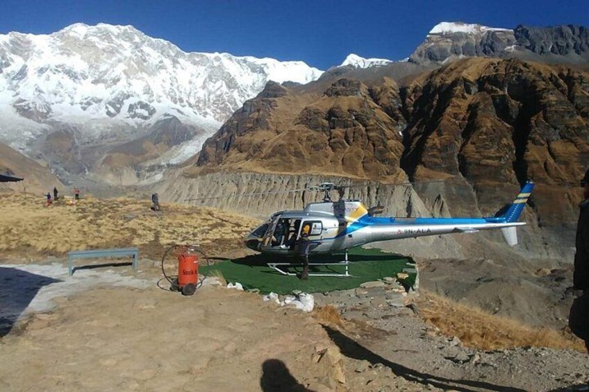 Un helicóptero estacionado sobre terreno de tierra con montañas al fondo. 3