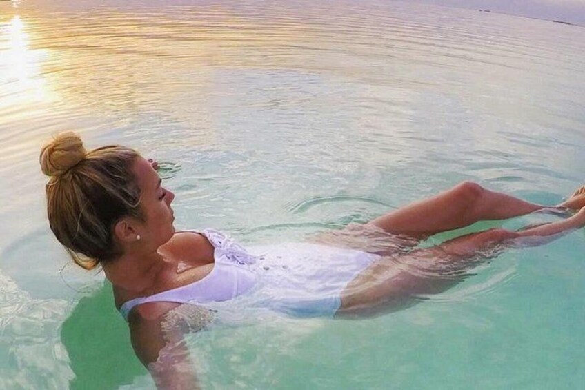 A person floating on a calm body of water with a clear sky. 3