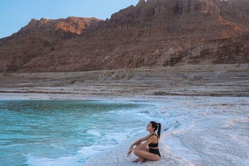 A person sitting on a snow-covered beach with a mountainous backdrop. 5