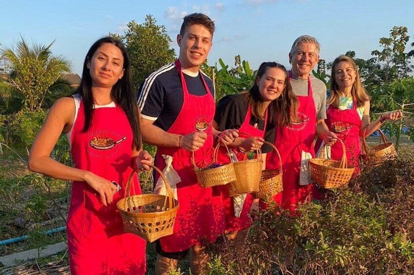 Un grupo de personas con delantales rojos y cestas en un jardín. 3