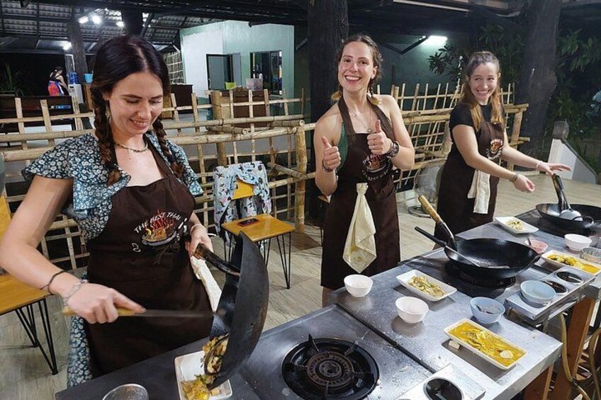 Tres personas cocinando al aire libre, con utensilios y alimentos sobre una mesa. 1