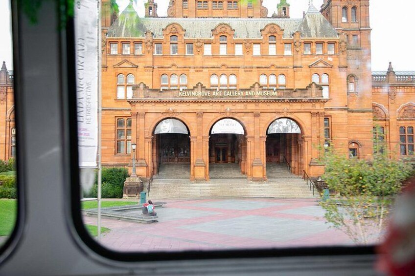 A large, historic building with arched entrances and a sign reading 'Kelvingrove Art Gallery and Museum.' 1