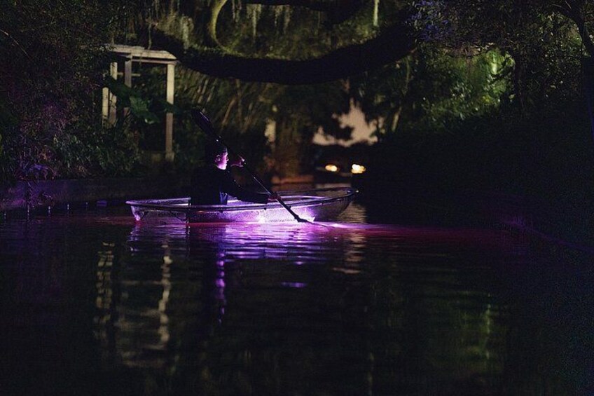 A person rowing a boat at night with purple lighting. 2