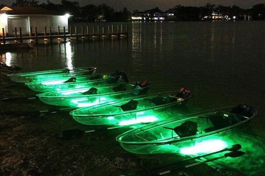 A row of canoes with green lights on a dock at night. 3