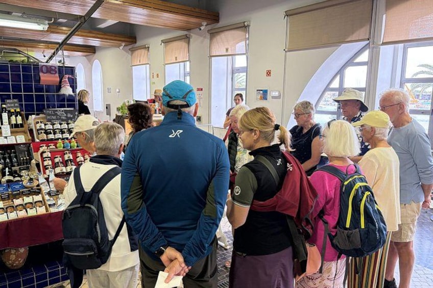 Eine Gruppe von Menschen an einem Marktstand, an dem verschiedene Waren ausgestellt sind. 4