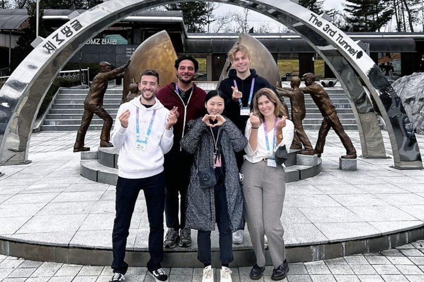 A group of people posing in front of a sculpture with inscriptions. 3