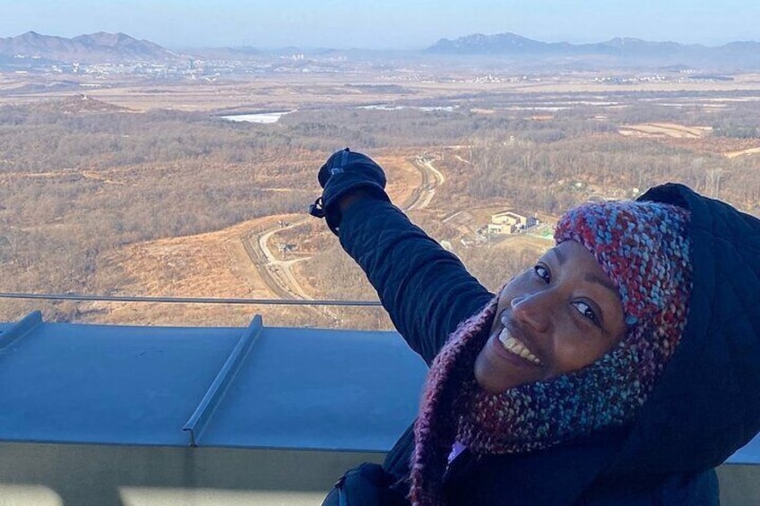 A person pointing at a landscape with mountains and a river. 2