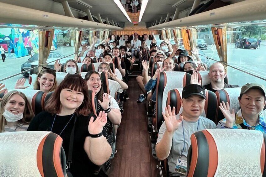 A group of people on a bus, waving and smiling. 5