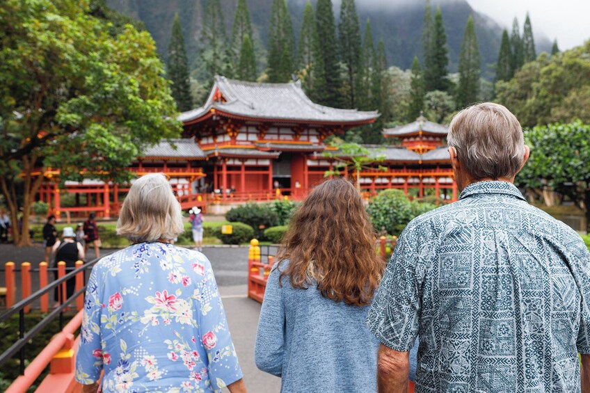 A traditional Japanese temple with a red and white facade, surrounded by lush greenery and mountains in the background. 1