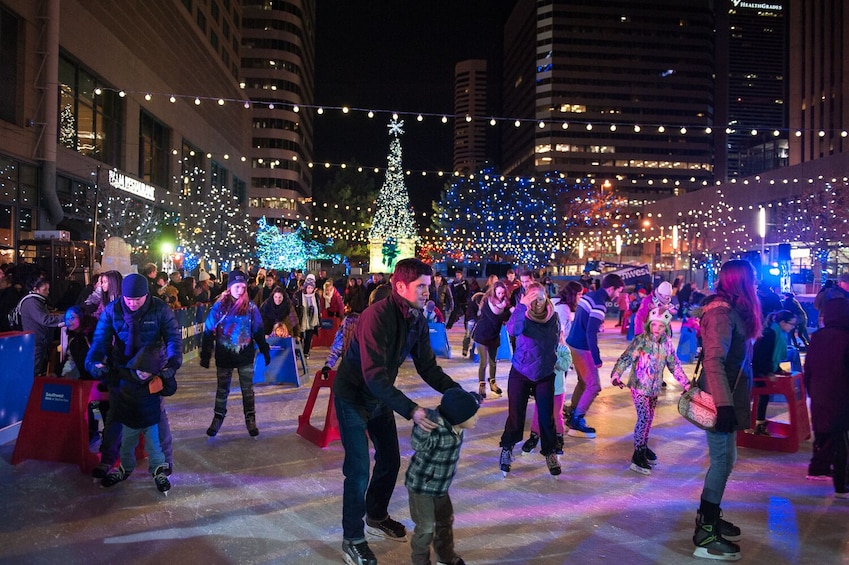 Personas patinando sobre hielo en una plaza de la ciudad por la noche. 4