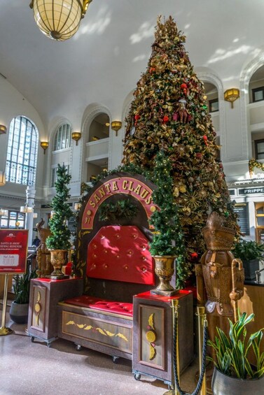 Un gran árbol de Navidad en un vestíbulo con una silla roja y detalles dorados. 5