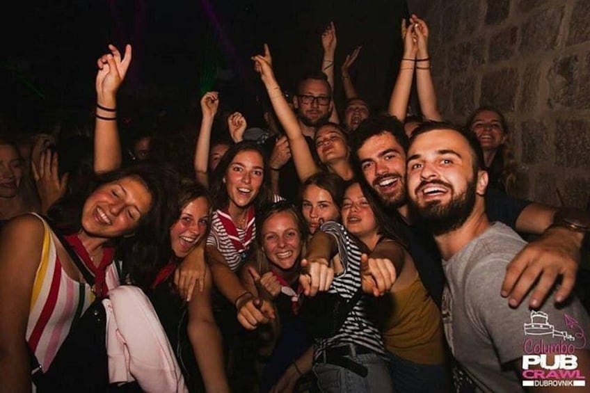 A group of people at a social event, possibly a party or gathering, with some individuals raising their hands. 4
